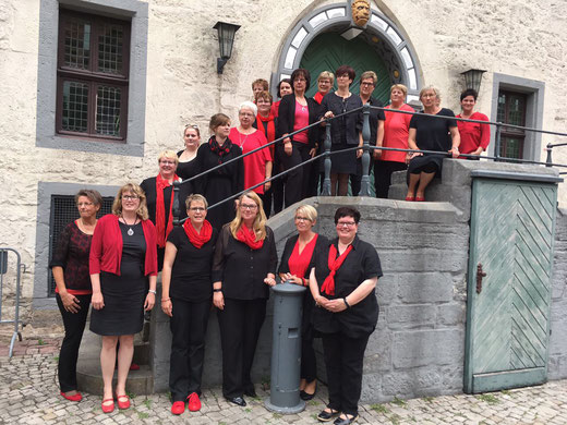 Gruppenfoto der Sängerinnen in schwarz-roter Kleidung auf einer Eingangstreppe